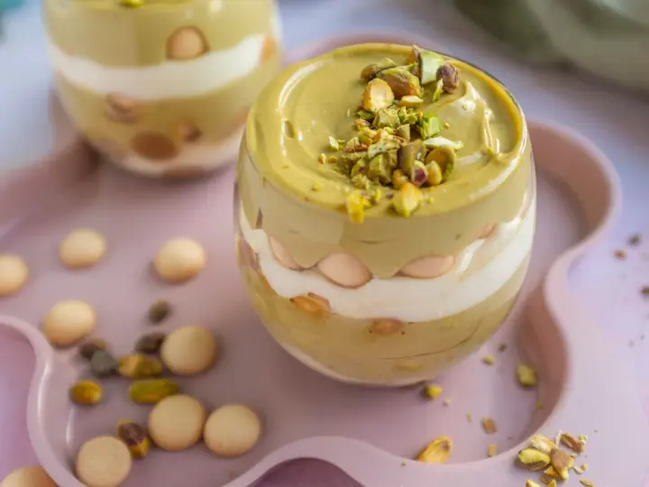 Pyszny deser w pucharku: krem pistacjowy z mascarpone, przełożony biszkoptami i posypany pistacjami.