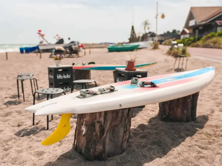 Windsurfbrett am Strand, ein echter Dahme Geheimtipp für Wassersportler. Gelbe Finne ragt aus dem Sand.