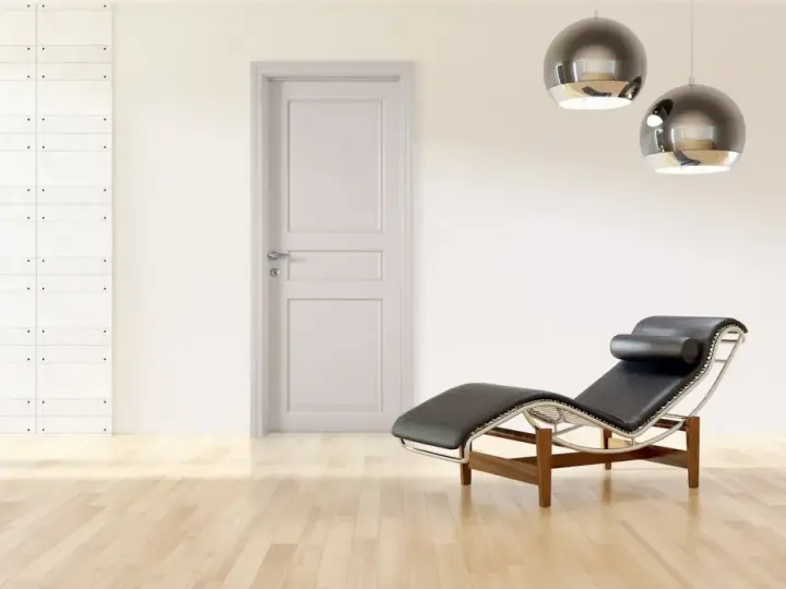 Divano in pelle nera e metallo, con un'elegante porta tortora e un muro con texture geometrica. Un perfetto abbinamento tortora e verde per un ambiente moderno.