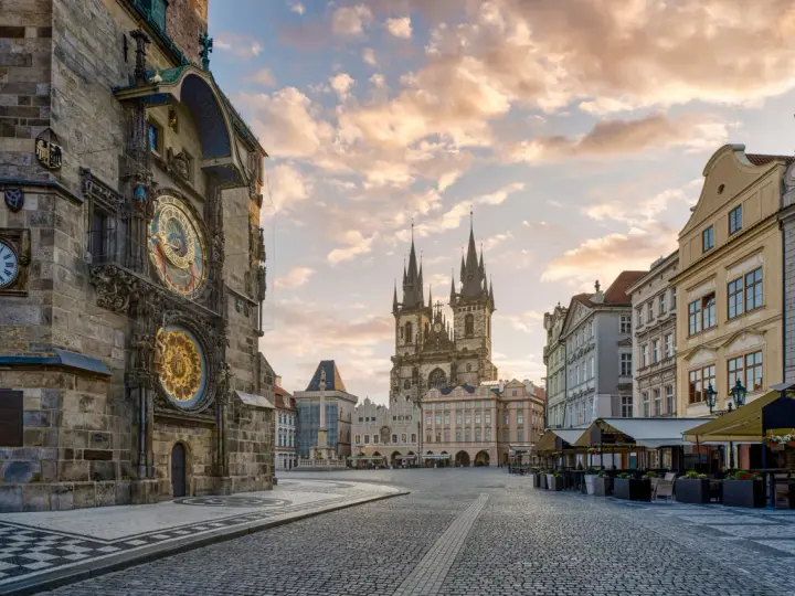 Praga co zobaczyć w jeden dzień: Ratusz Staromiejski z zegarem astronomicznym i Kościół Marii Panny przed wieżami w blasku porannego słońca.