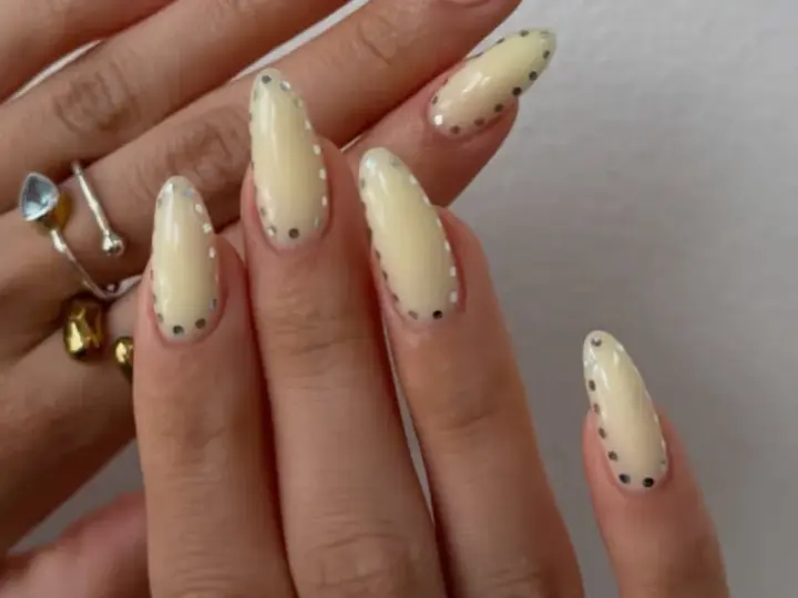 Modne paznokcie wzory galeria: kremowe migdałki z błyszczącymi kropkami. Delikatny manicure, który przyciąga wzrok.