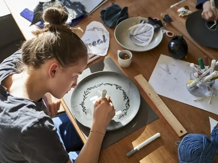 Dziewczyna maluje wzór na talerzu, tworząc własny przepis na masę porcelanową.