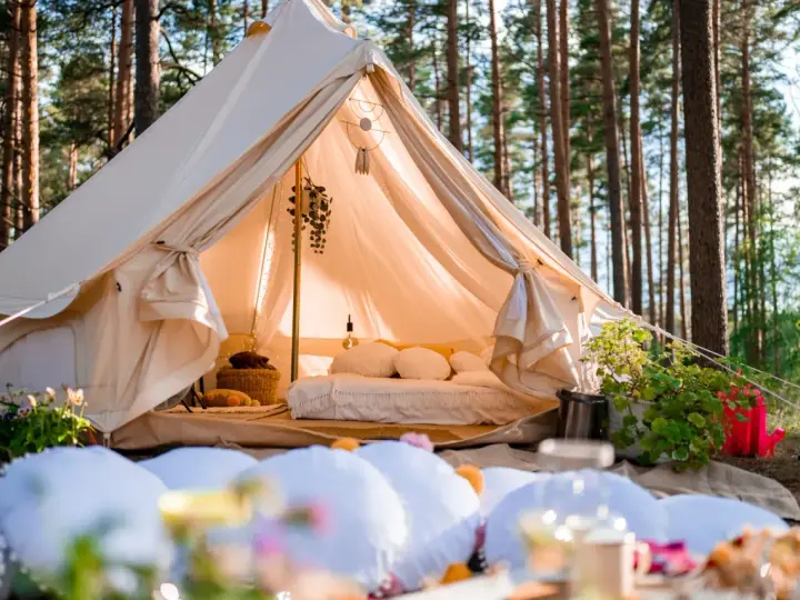 Glamping co to? Luksusowy namiot w lesie, z wygodnym łóżkiem i dekoracjami, zaprasza do odpoczynku.