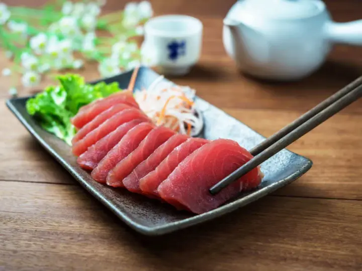 Vackert upplagd tonfisk sashimi på en tallrik, redo att avnjutas med en god vin.