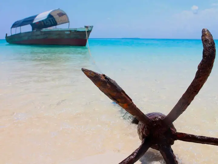 Kotwica na plaży, łódź na turkusowym morzu. Idealne miejsce na Zanzibar wycieczki fakultatywne.