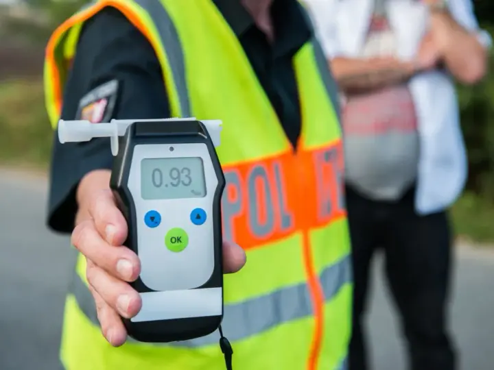 Policjant pokazuje alkomat z wynikiem 0.93 promila. To przekroczenie dopuszczalnej ilości alkoholu w wydychanym powietrzu.