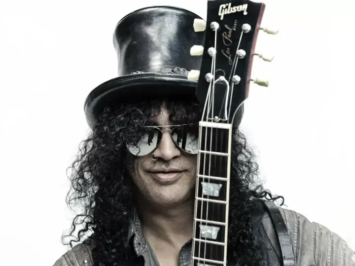 Le guitariste Slash, avec son chapeau haut-de-forme et ses lunettes de soleil, pose avec sa guitare Gibson Les Paul.