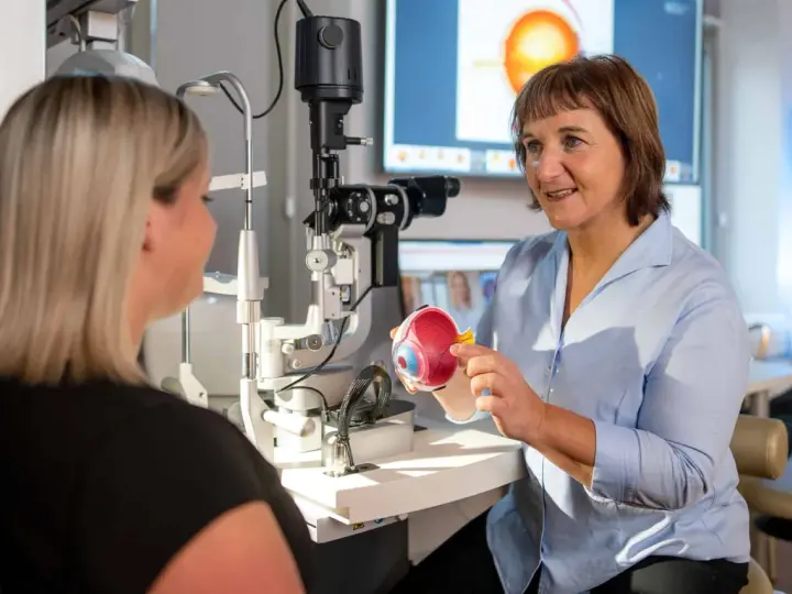 Augenarzt erklärt Modellauge. Mögliche Behandlung: Augen lasern. Krankschreibung wird besprochen.