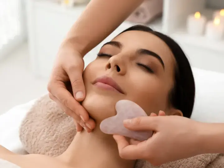 Relaksacyjny masaż twarzy kamieniem gua sha. Delikatne ruchy kamienia poprawiają krążenie i odmładzają skórę.