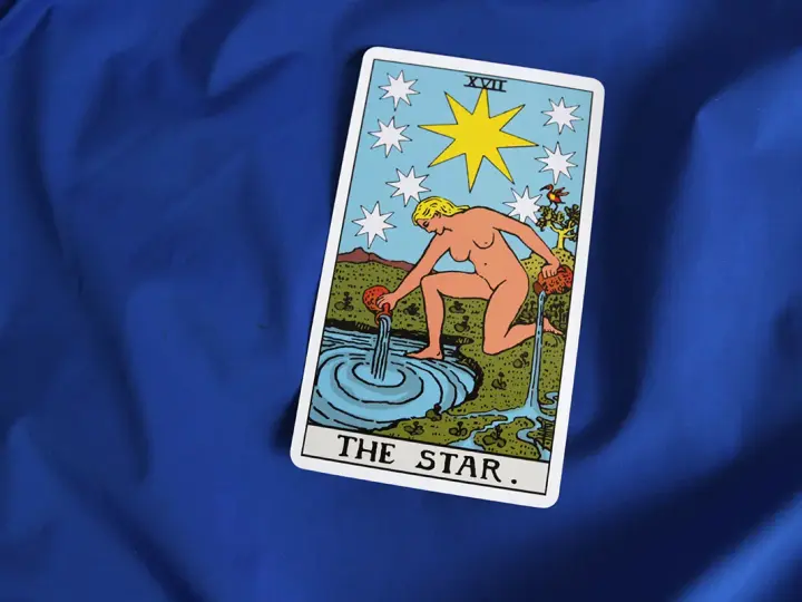Karta XVII - Gwiazda Tarot. Kobieta wylewa wodę z dzbanów do stawu, symbolizując nadzieję i odnowę.