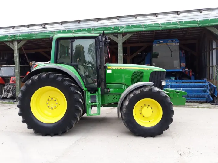 Zielony traktor John Deere 6820, z żółtymi felgami, gotowy do pracy. Dane techniczne tego modelu są imponujące.