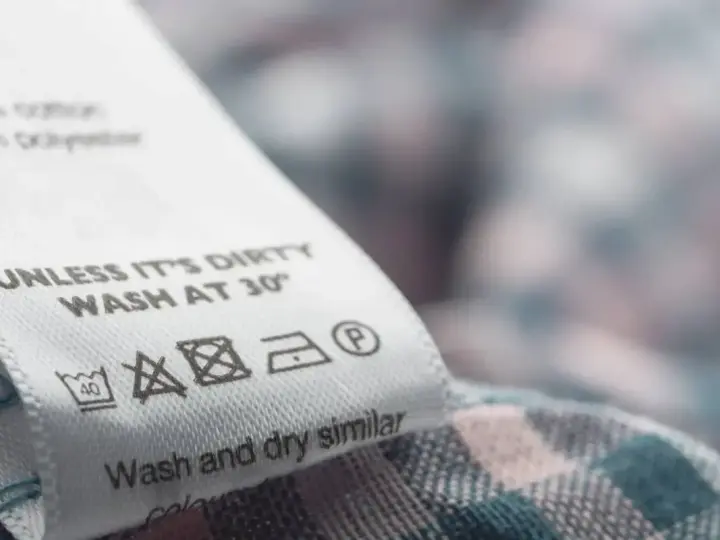Metka z instrukcją prania: prać w 30°C, nie wybielać, prasować w niskiej temperaturze, dopuszczalne czyszczenie chemiczne.