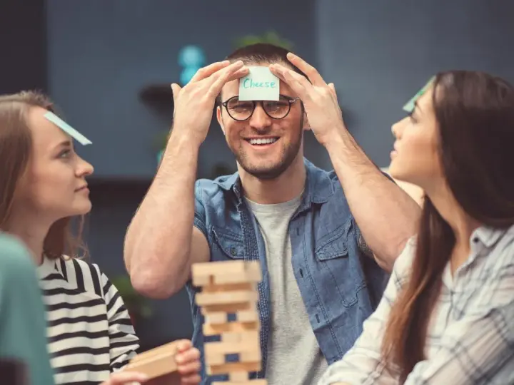 Amigos jugando a "adivina la palabra" en su frente, parte de juegos para fiestas adultos.