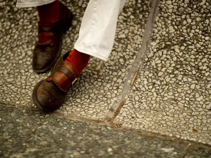 Scarpe marroni uomo con fibbia e calzini rossi, perfette per un look casual chic.