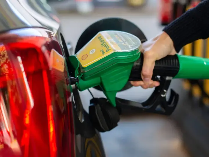 Tankstelle: Eine Hand betankt ein Auto mit dem grünen Zapfhahn. So behältst du im Blick, wie viel verbraucht dein Auto.