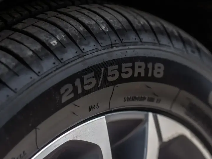 Zbliżenie na bieżnik opony z widocznym oznaczeniem 215/55R18.