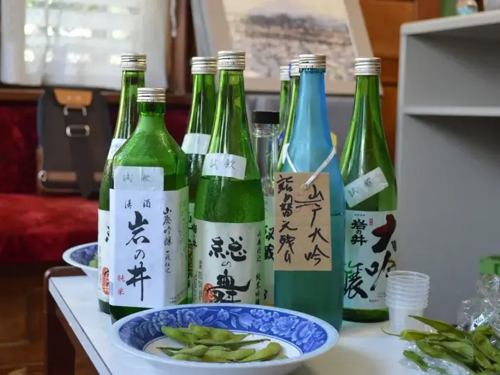 Butelki z japońskim alkoholem, idealne, gdy szukasz, czym zastąpić sake. Obok miseczka z edamame.
