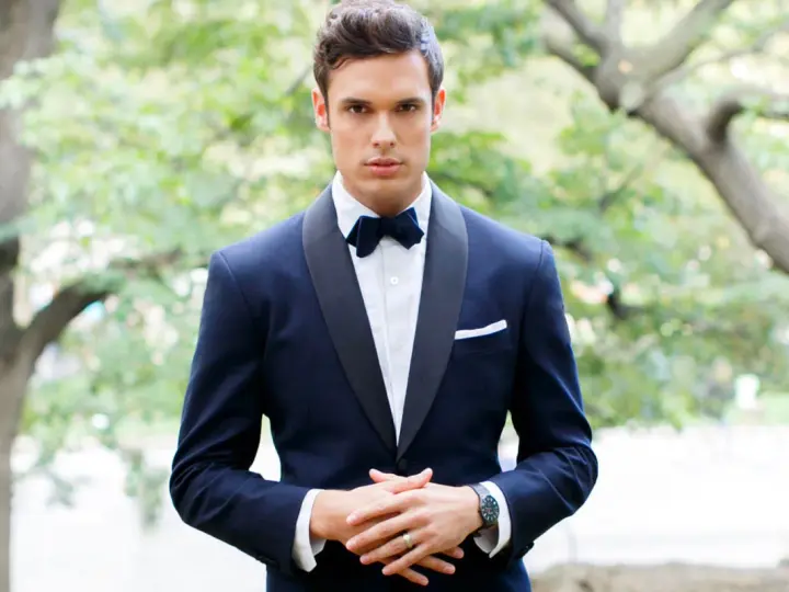 Uomo con smoking blu scuro, papillon e fazzoletto bianco. Il colore abito padre dello sposo è elegante e raffinato.