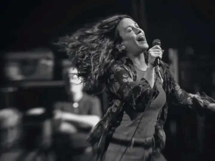 Energetyczny alanis morissette koncert, wokalistka śpiewa z pasją, włosy rozwiane w locie.