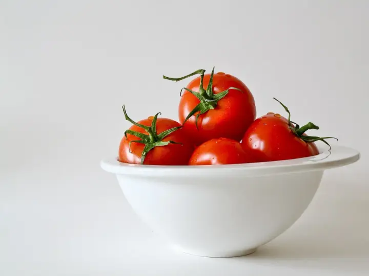 Kilka soczystych pomidorów w białej misce. Niska zawartość pomidor kcal sprawia, że są idealne na zdrową przekąskę.