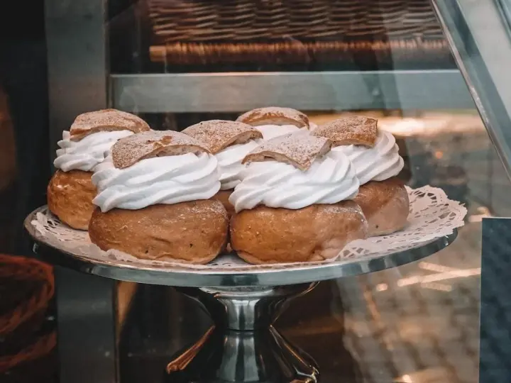 Sju semlor på ett fat, redo för pannkakans dag. Krämig grädde och pudrat socker.