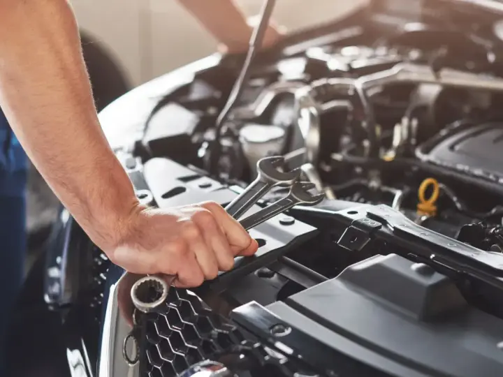Mechanik sprawdza objawy awarii pompy paliwa Audi A4 B6 1.8T. W dłoni trzyma klucze.
