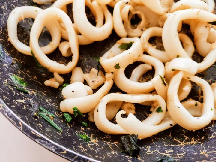 Anelli di totano in padella, dorati e profumati con erbe aromatiche, pronti per essere gustati.