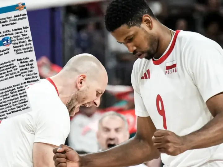 Daniel Stępień, siatkarz w białej koszulce z numerem 9 i godłem Polski, świętuje z kolegą z drużyny.