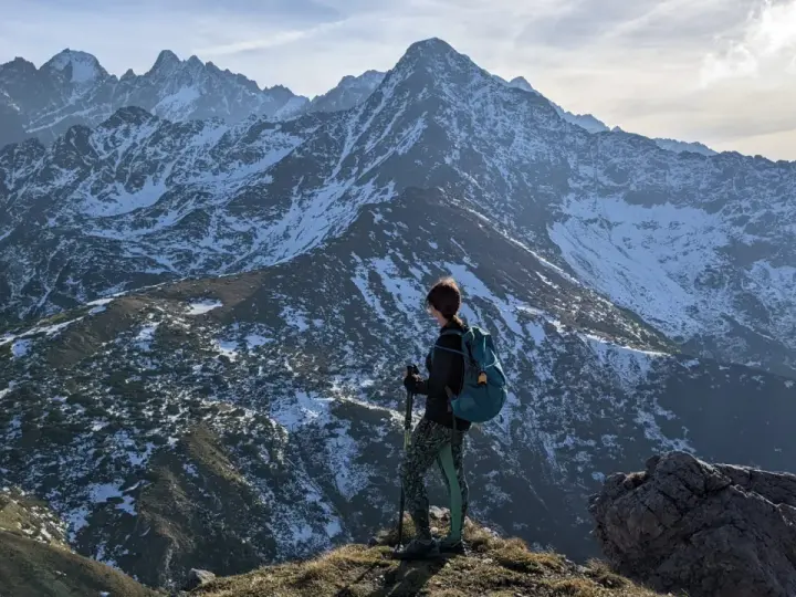 Osoba z plecakiem i kijkami podziwia zimowe Tatry Bielskie. Wspaniałe widoki na szlaki.
