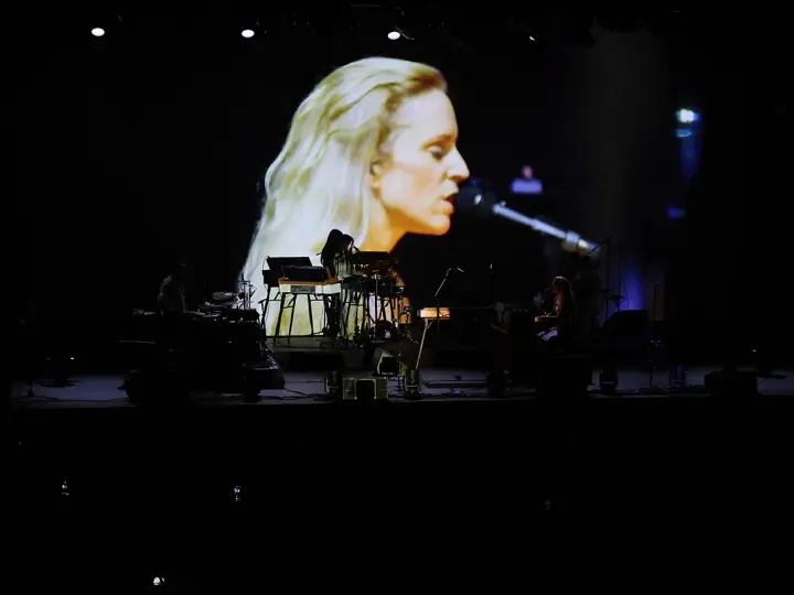 Agnes Obel na ekranie i zespół na scenie podczas koncertu.