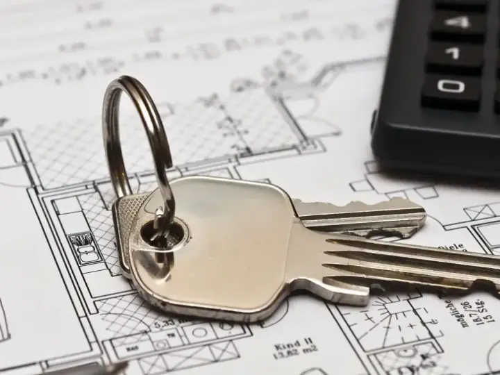 Schlüssel und Taschenrechner liegen auf Bauplänen. Ein Haus mit Garage und Zimmern ist zu sehen. Ideal für Mietrecht Oberhausen.
