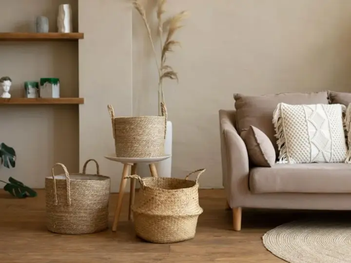 Przytulny salon w stylu boho: plecione kosze, beżowa kanapa z makramową poduszką i suszone trawy.