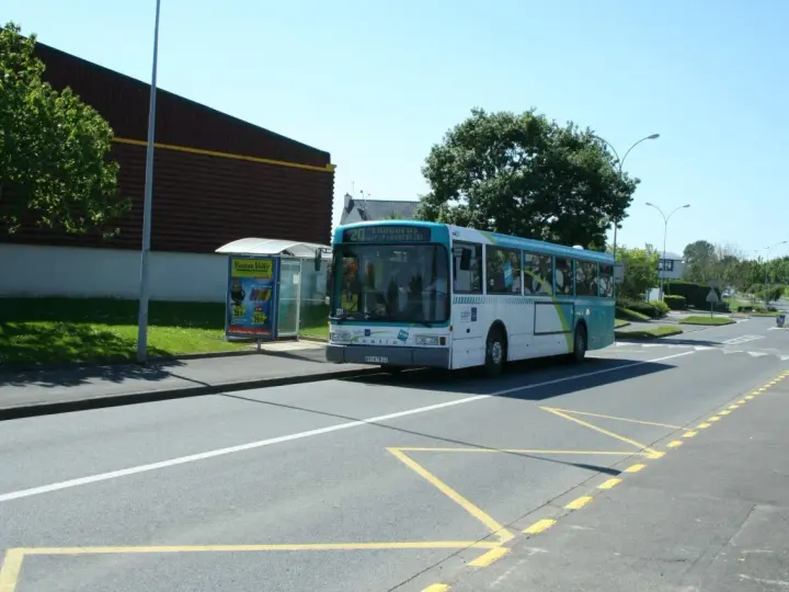Un bus scolaire s'arrête à un arrêt de bus, respectant le code de la route. Le soleil brille sur la route.