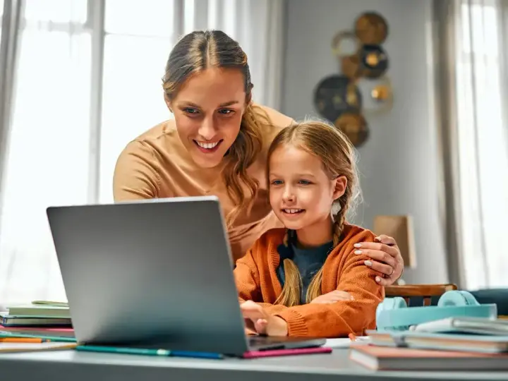 Mama pomaga córce w nauce online. Dni opieki na dziecko mogą być pełne wspólnych chwil przy komputerze.