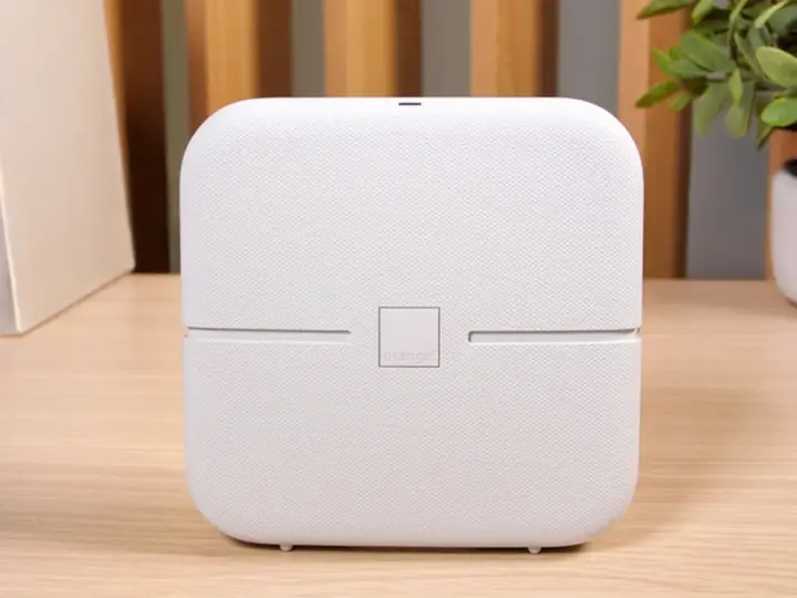 Biały router funbox 7 Orange, z logo operatora, stoi na drewnianym biurku obok książek i rośliny.