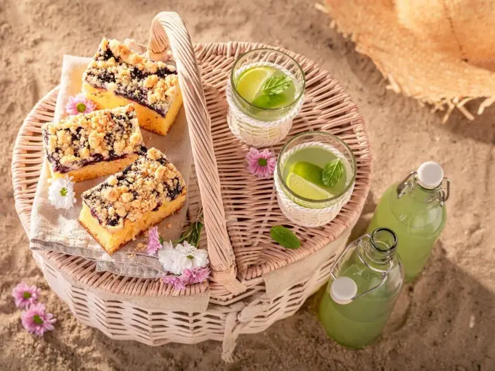 Idealne co na piknik: ciasto z jagodami, orzeźwiająca lemoniada i słomkowy kapelusz na plaży.