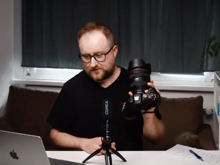 Mężczyzna prezentuje aparat fotograficzny, omawiając elementy kursu fotografii dla początkujących.