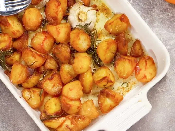 Ugnsrostad potatis med vitlök och rosmarin i en vit ugnsform. Perfekt tillbehör som doftar ljuvligt!