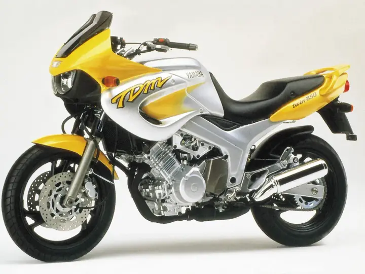 Żółto-srebrny motocykl Yamaha TDM 850 z charakterystycznym napisem "TDM" na baku. Gotowy na przygodę!