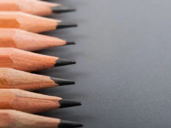 Filas de lápices de madera con puntas afiladas, listos para dibujar. La dureza de los lápices varía, ofreciendo distintas tonalidades.