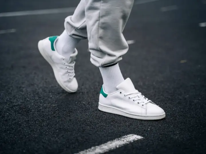 Un paio di sneakers bianche con dettagli verdi, simbolo di stile e comfort. Il loro significato va oltre la moda, rappresentando libertà di movimento.