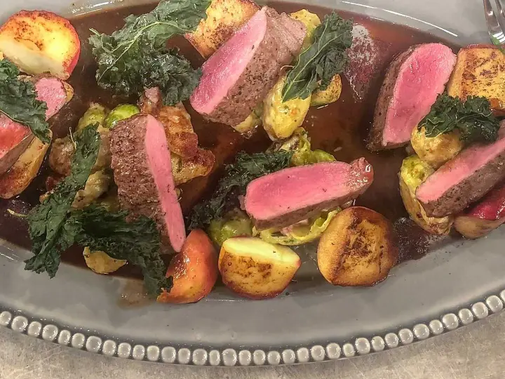 Vildsvinskött med perfekt rosa temperatur, serverat med rostade potatisar, brysselkål och grönkål i en mustig sås.