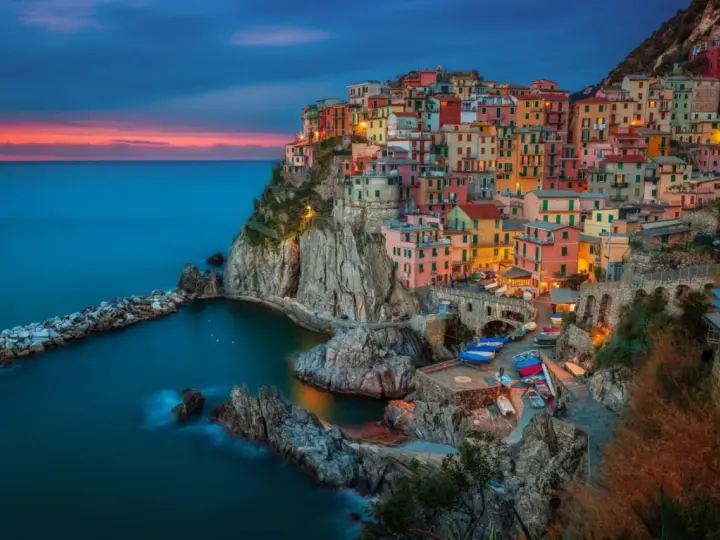 Kolorowe domy Cinque Terre, jedne z najpiękniejszych regionów Włoch, wznoszą się na klifie nad morzem o zachodzie słońca.