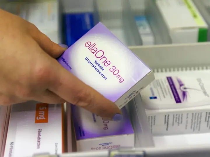 Hand greift nach ellaOne 30mg Tablette. Informationen zu ellaOne Nebenwirkungen sind auf der Packung zu finden.
