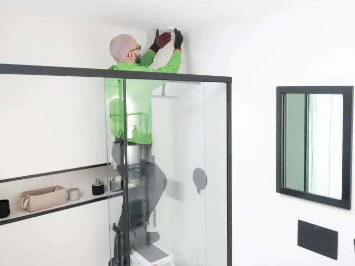 Hombre instala extractor baño en el techo.