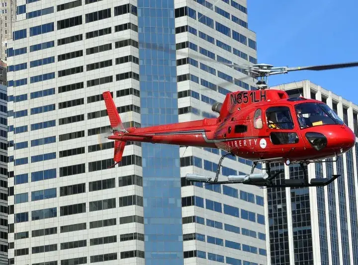 Czerwony helikopter Liberty przelatuje obok wieżowców. Zastanawiasz się, ile kosztuje lot helikopterem nad Nowym Jorkiem?