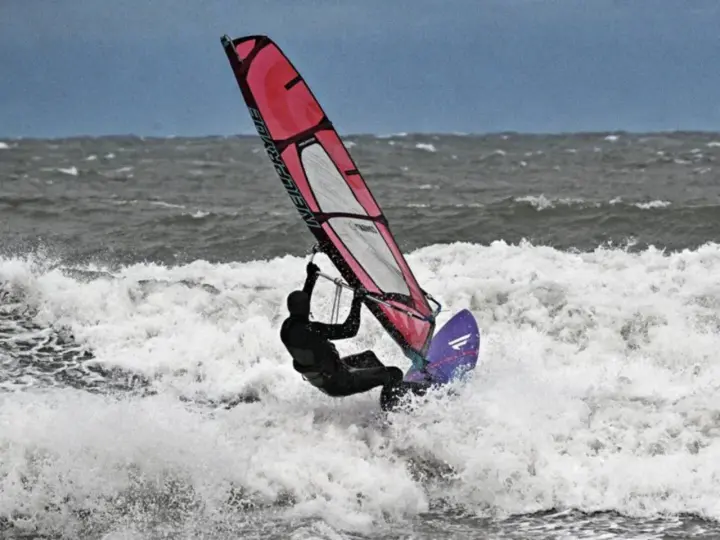 Windsurferin in Aktion auf der Ostsee, die mit ihrem Segel über die Wellen springt.