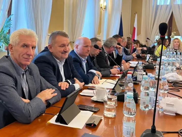 Mężczyźni przy stole obradują, dyskutując o przyznaniu absolutorium.