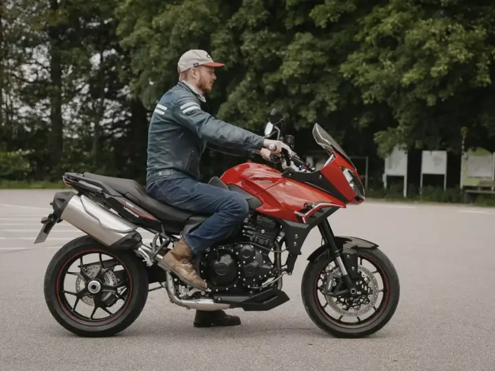 Mężczyzna na czerwonym motocyklu Triumph Tiger 1050. Poznaj jego dane techniczne i możliwości.