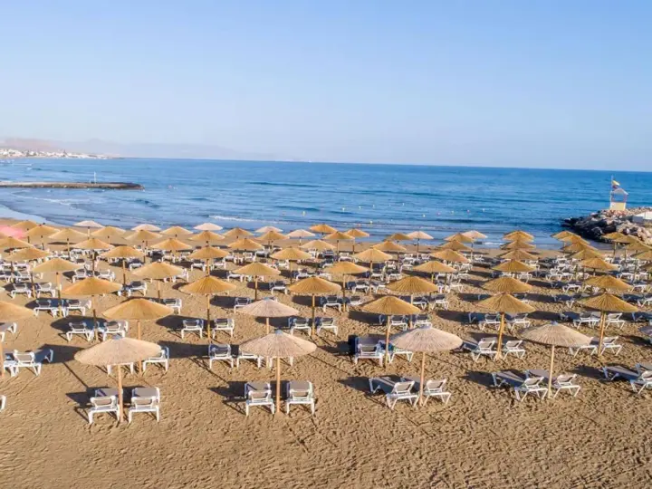 Plaża sol marina beach crete z rzędami leżaków i parasoli, gotowa na gości. Błękitne morze i niebo tworzą idealne tło.